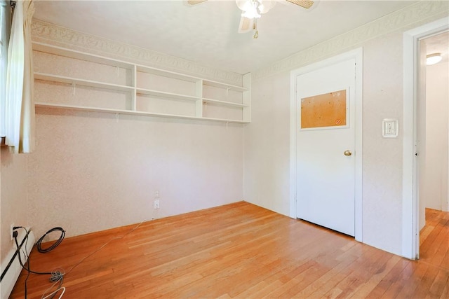 spare room featuring a ceiling fan, baseboard heating, and hardwood / wood-style flooring