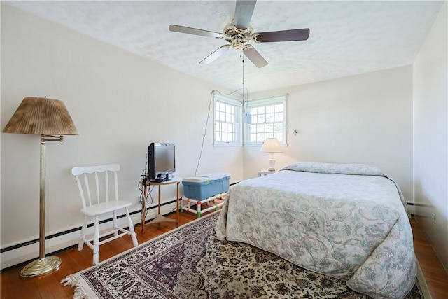 bedroom featuring baseboard heating, ceiling fan, and wood finished floors
