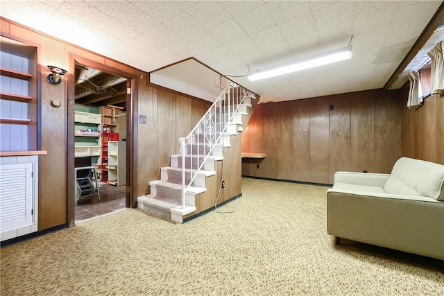 finished basement featuring stairs, wooden walls, and carpet floors