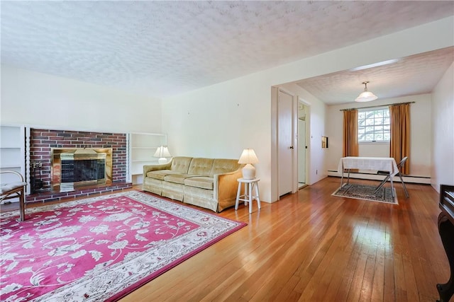 living room with a textured ceiling, a fireplace, a baseboard radiator, and hardwood / wood-style flooring
