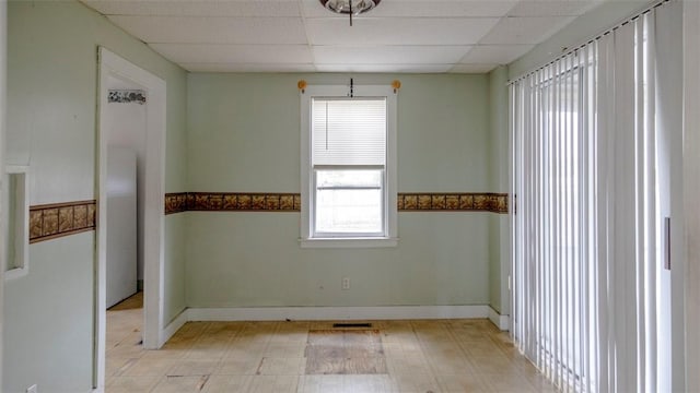 unfurnished room featuring a paneled ceiling, light floors, baseboards, and visible vents