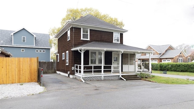 traditional style home featuring covered porch and fence