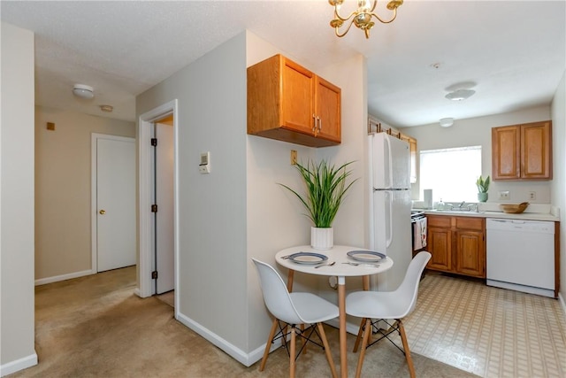 kitchen with a sink, brown cabinets, dishwasher, light countertops, and baseboards