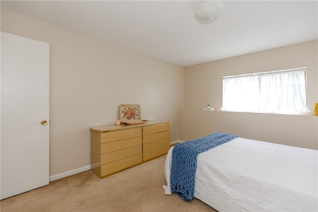 bedroom with light colored carpet and baseboards
