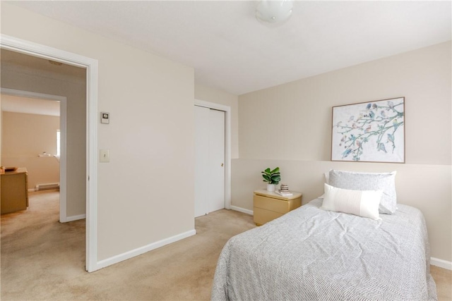 bedroom featuring light colored carpet, baseboards, and a closet