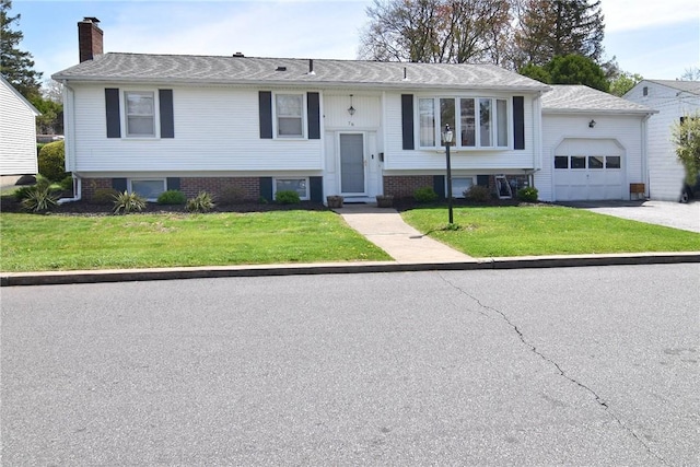 76 Oregon Ave, North Providence, RI 02911 - raised ranch featuring a front yard, driveway, a chimney, and a garage