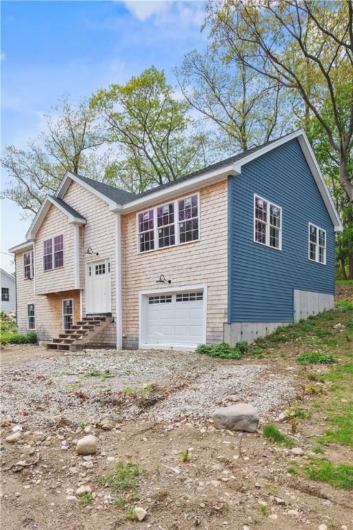 view of front facade with dirt driveway, a garage, and entry steps