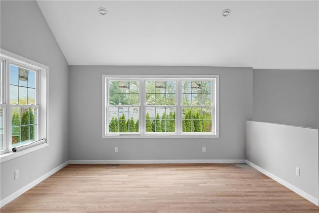 spare room with lofted ceiling, baseboards, visible vents, and light wood-style floors