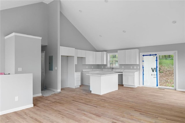 kitchen with electric panel, a kitchen island, high vaulted ceiling, and white cabinets