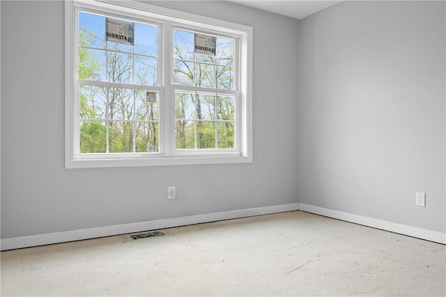 empty room featuring baseboards, a healthy amount of sunlight, and visible vents