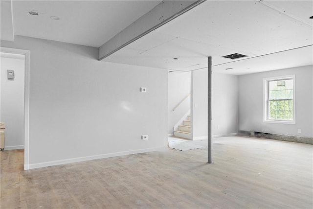below grade area featuring baseboards, stairway, and light wood finished floors