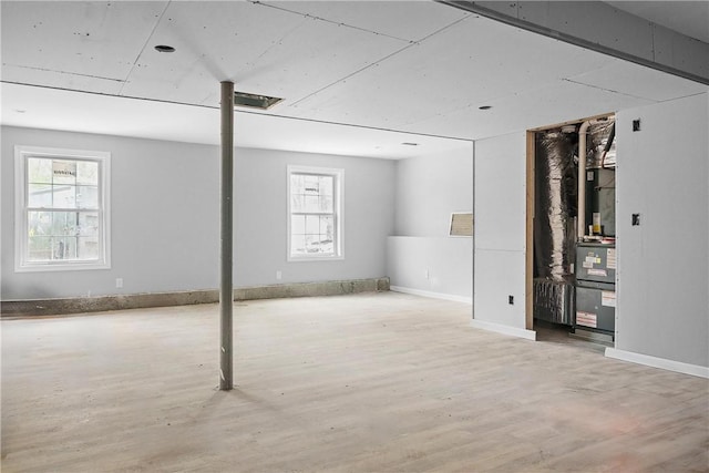 basement with baseboards, a healthy amount of sunlight, and wood finished floors