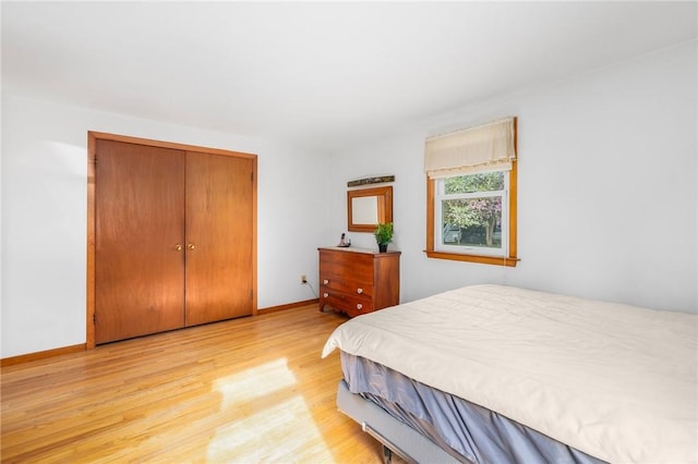 bedroom featuring a closet, light wood-style flooring, and baseboards