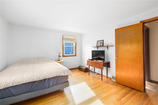 bedroom with baseboards, visible vents, and wood finished floors