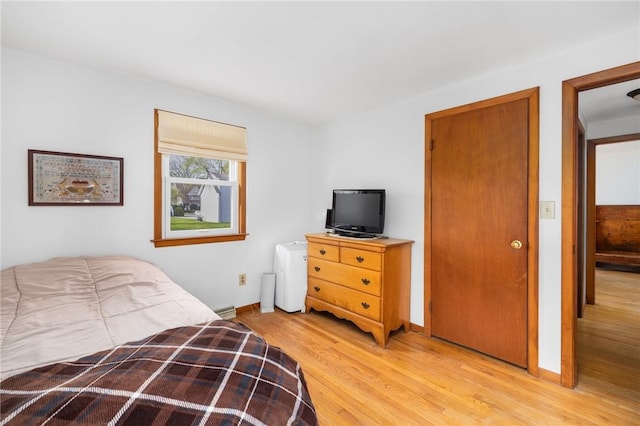 bedroom with baseboards, light wood-type flooring, and baseboard heating