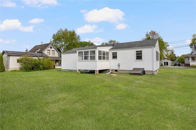 rear view of house featuring a lawn and a sunroom