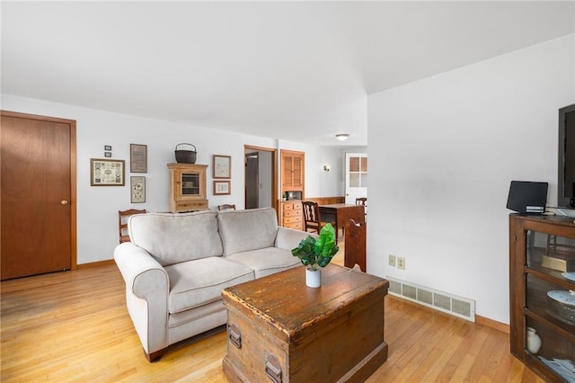 living room with visible vents, light wood-style flooring, baseboards, and a fireplace