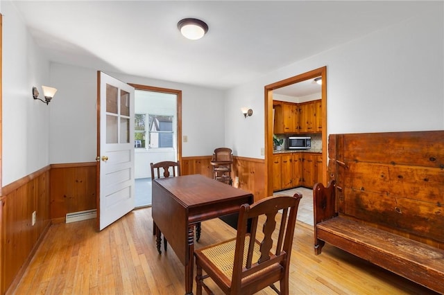 dining room with wainscoting, light wood finished floors, and wooden walls