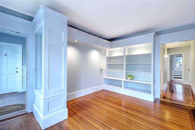 unfurnished room featuring ornamental molding, wood finished floors, baseboards, and a baseboard heating unit