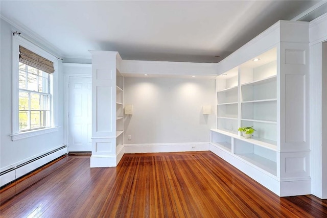 spare room featuring wood finished floors, baseboards, a baseboard heating unit, and built in shelves