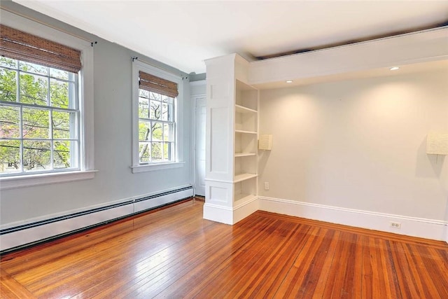 spare room with a baseboard heating unit, baseboards, plenty of natural light, and hardwood / wood-style flooring