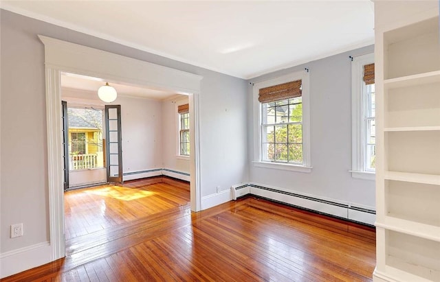 spare room with baseboards, hardwood / wood-style floors, and a baseboard heating unit