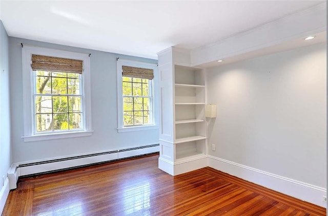 empty room with baseboards, wood finished floors, a baseboard radiator, and recessed lighting
