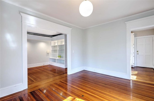 spare room featuring wood finished floors, baseboards, and ornamental molding