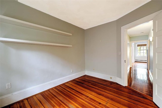 spare room featuring a baseboard radiator, wood-type flooring, and baseboards