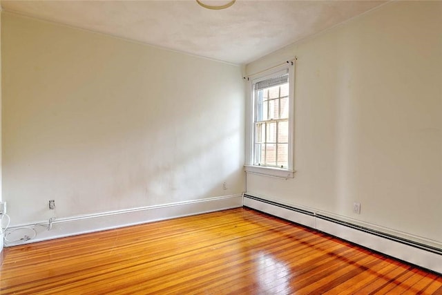 empty room featuring light wood-type flooring, baseboards, and baseboard heating