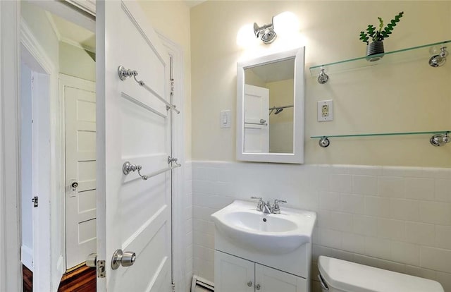 bathroom featuring tile walls, a baseboard radiator, toilet, vanity, and a wainscoted wall