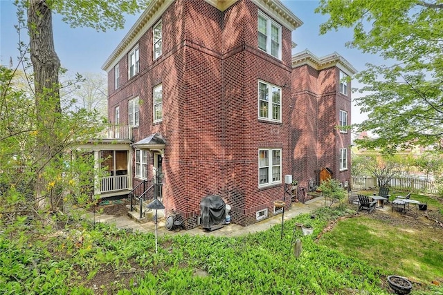 view of property exterior with a patio, brick siding, and fence