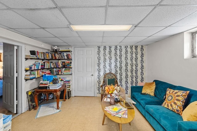 living area featuring tile patterned floors and a paneled ceiling