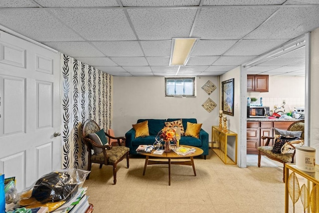 living area with light floors, a baseboard heating unit, and a drop ceiling