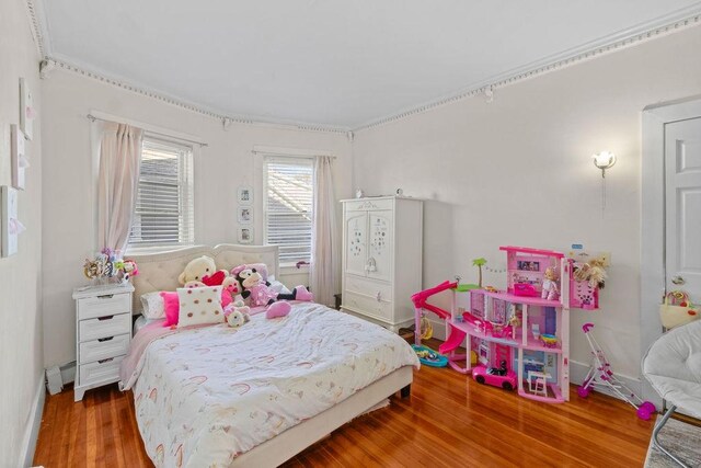 bedroom featuring wood finished floors, baseboards, and a baseboard heating unit