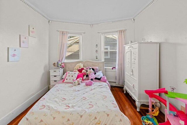 bedroom with wood finished floors and a baseboard radiator