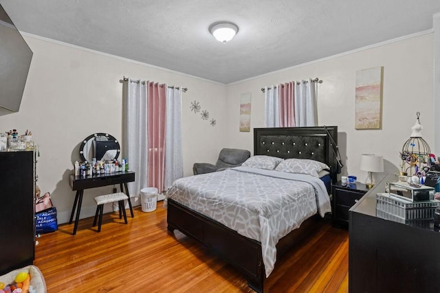 bedroom featuring a textured ceiling, wood finished floors, and ornamental molding