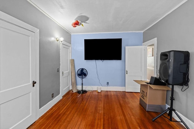 workout room with wood finished floors, baseboards, and ornamental molding