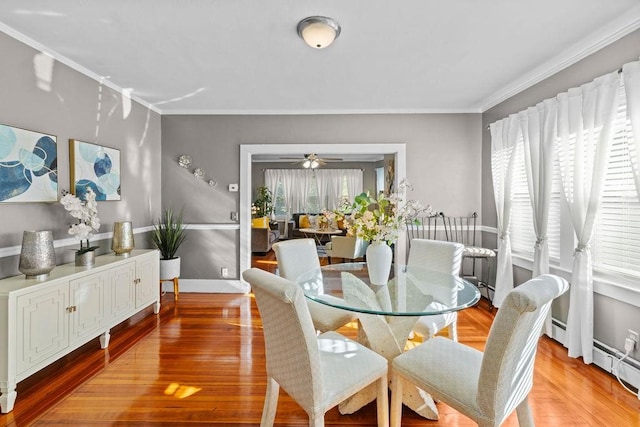 dining space with baseboards, ornamental molding, ceiling fan, and wood finished floors