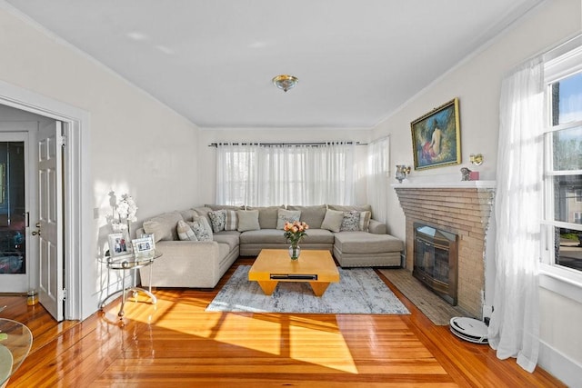 living area with a fireplace, crown molding, and wood finished floors