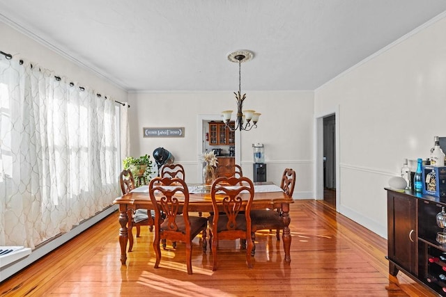 dining area with an inviting chandelier, ornamental molding, wood-type flooring, and a baseboard heating unit