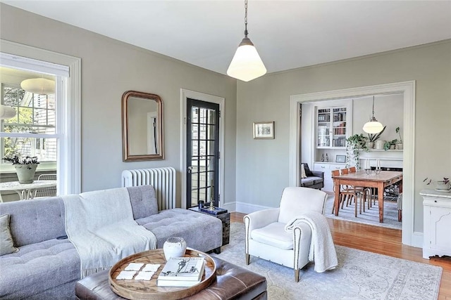 living area with a wealth of natural light, wood finished floors, and radiator heating unit