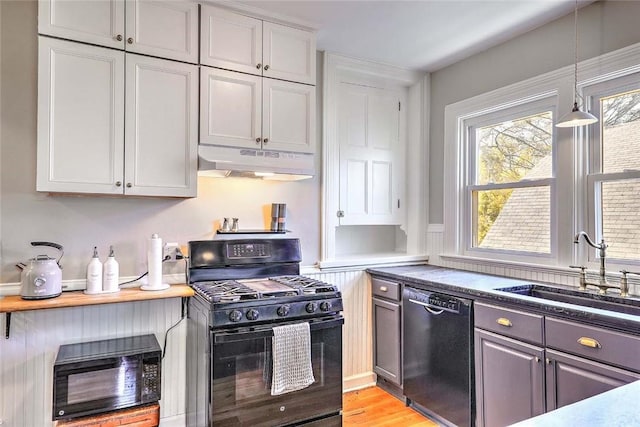 kitchen with a sink, decorative light fixtures, black appliances, under cabinet range hood, and light wood-style flooring