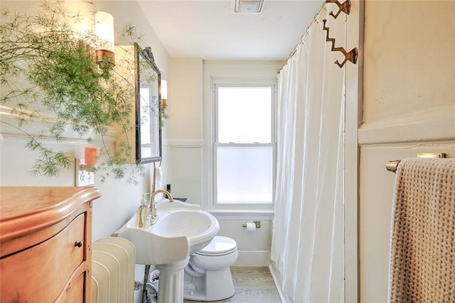 bathroom featuring a sink, toilet, and a healthy amount of sunlight