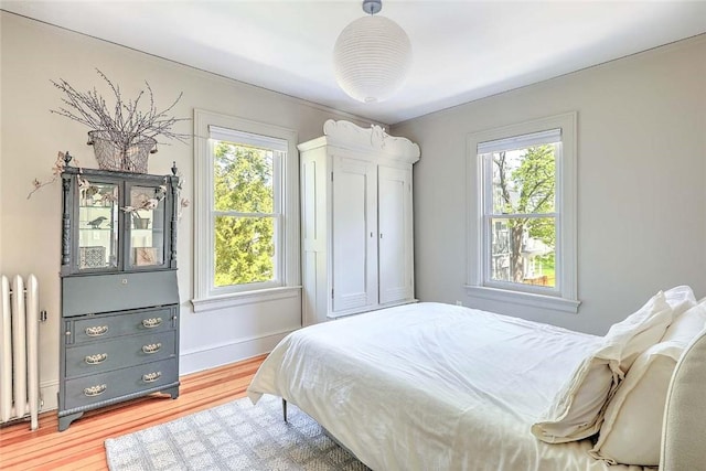 bedroom with baseboards, radiator heating unit, and wood finished floors