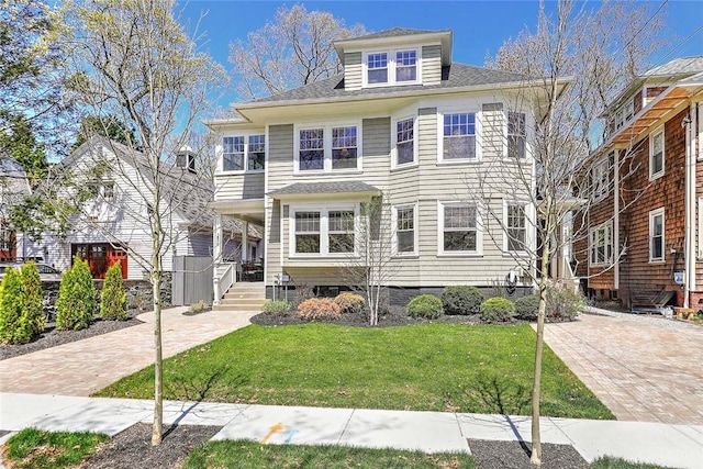 american foursquare style home with a porch, a shingled roof, and a front yard