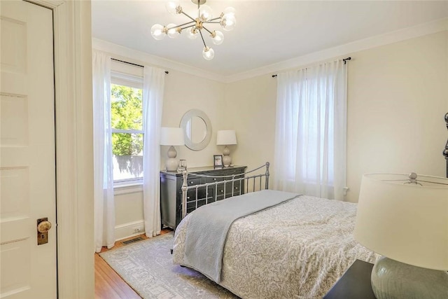 bedroom featuring baseboards, visible vents, a chandelier, crown molding, and wood finished floors