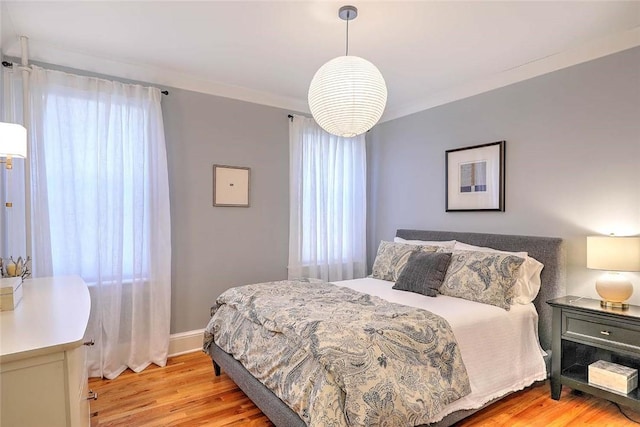 bedroom featuring ornamental molding, light wood-type flooring, and multiple windows