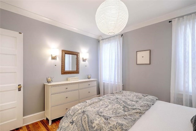 bedroom featuring crown molding, light wood-style flooring, and baseboards