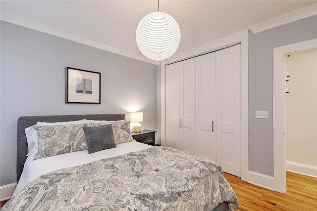 bedroom featuring a closet, light wood-style flooring, and baseboards